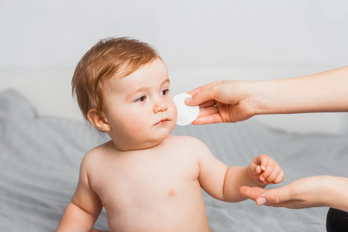 nettoyer le visage de bébé avec un coton lavable