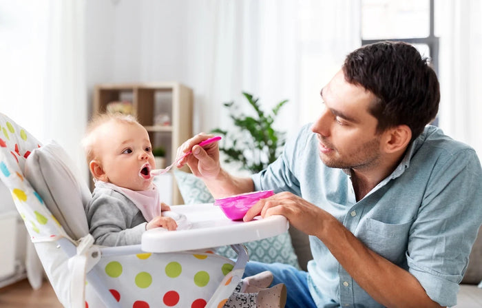 papa donne une cuillère de purée à bébé